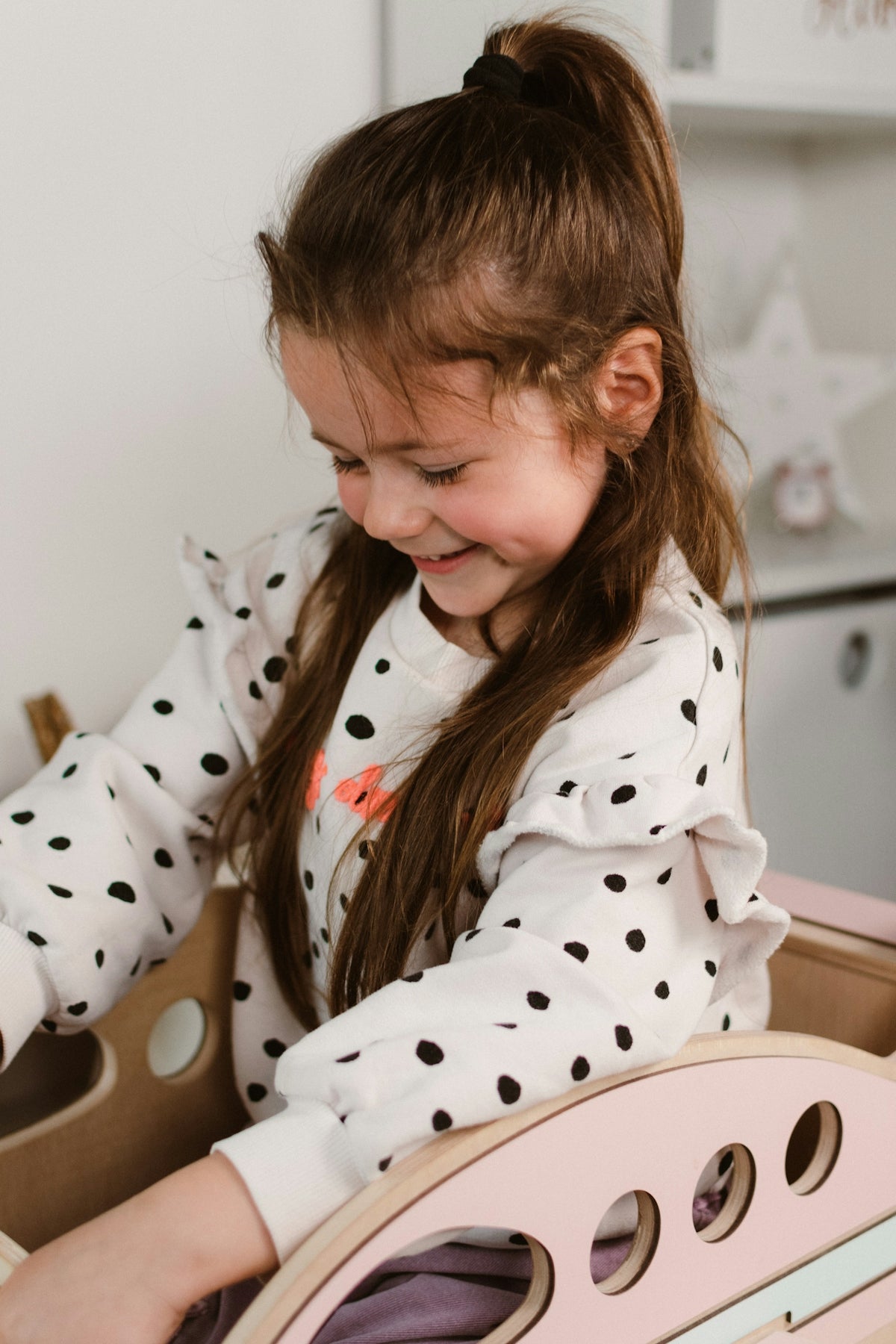 a little girl playing with a wooden toy car