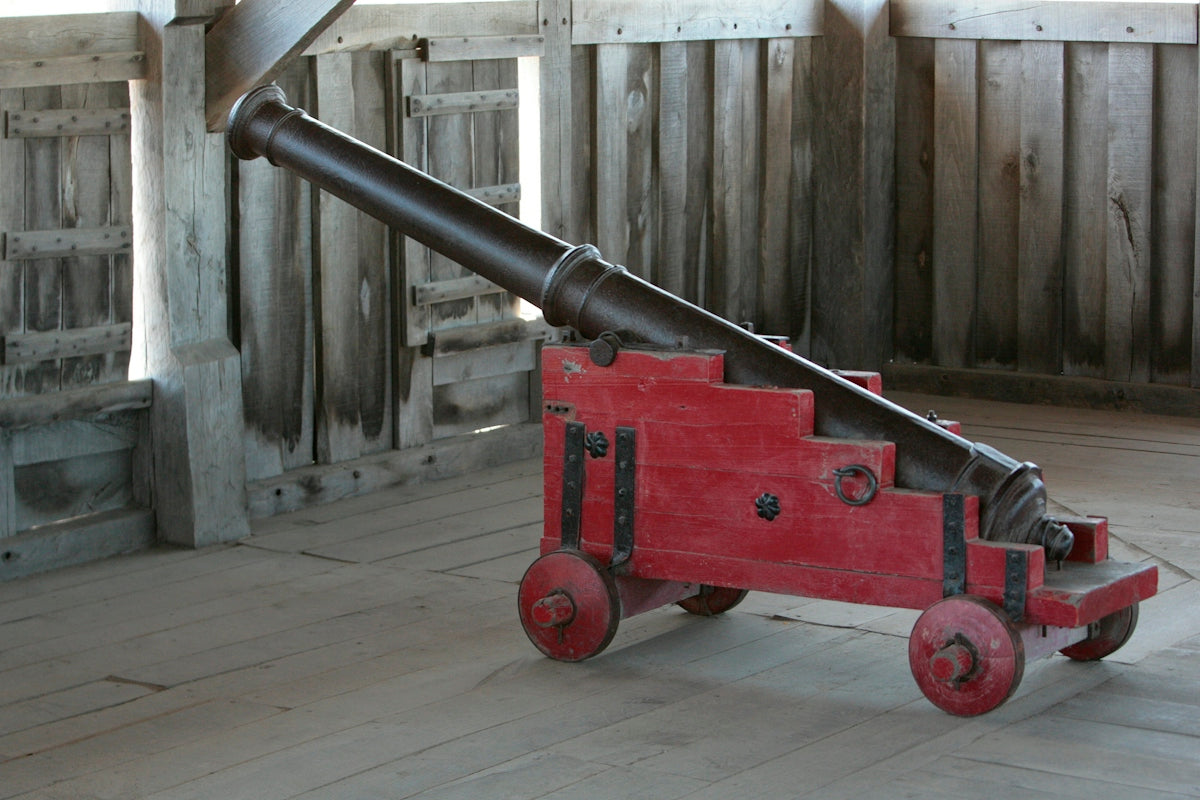 A red cannon sitting on top of a wooden floor