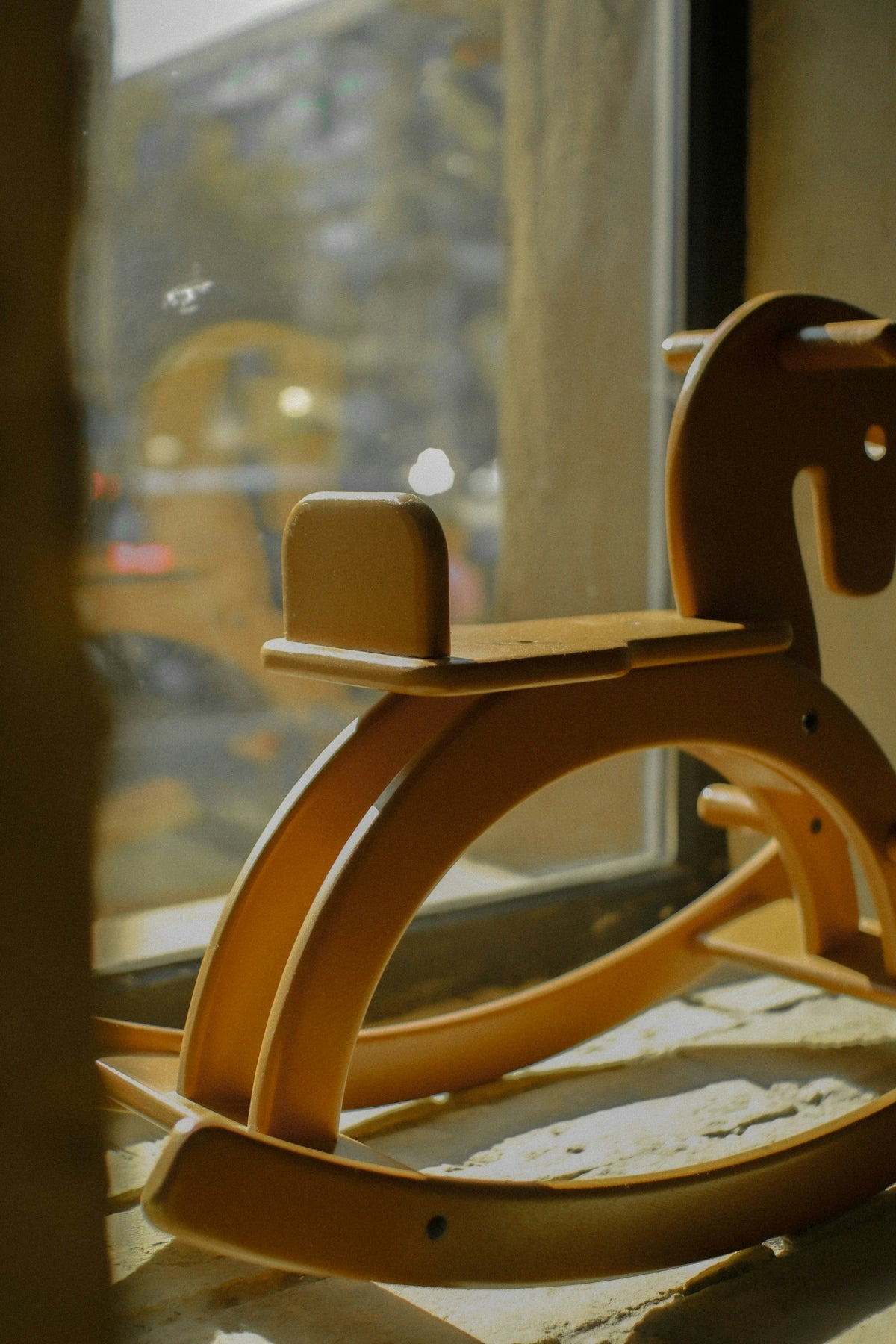 A wooden rocking horse sitting on a window sill