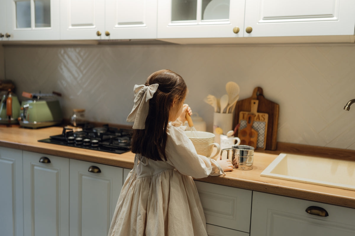 A little girl standing in a kitchen next to a sink