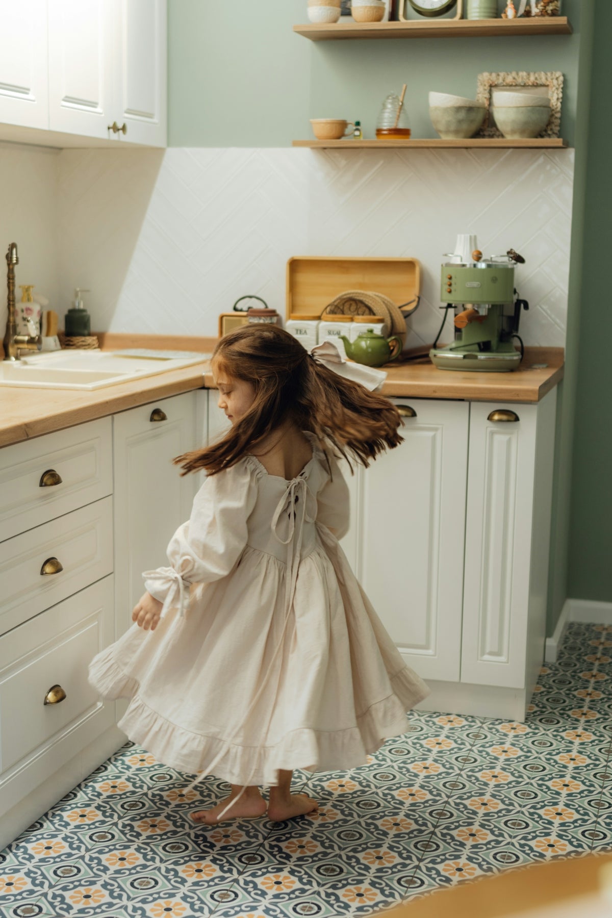 A little girl standing in a kitchen next to a sink