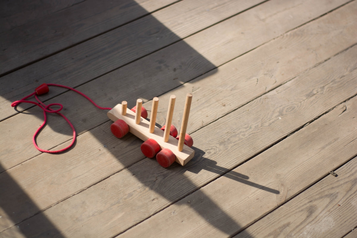 A wooden toy wagon sits on the wooden floor.