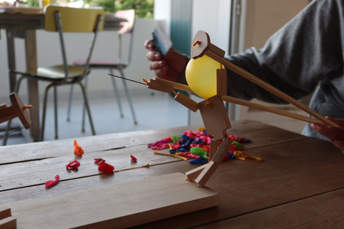 A wooden figure is shooting a water balloon.